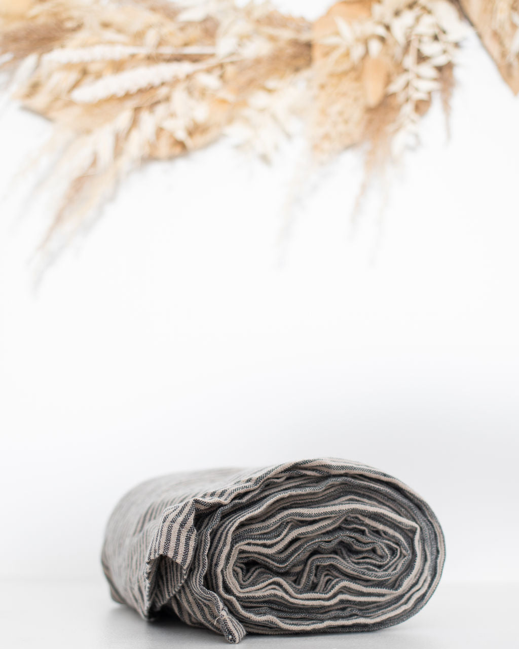 Rolled-up gray and white striped linen ring sling on a white background