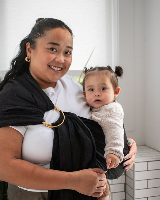 Woman holding a baby in a black linen sling