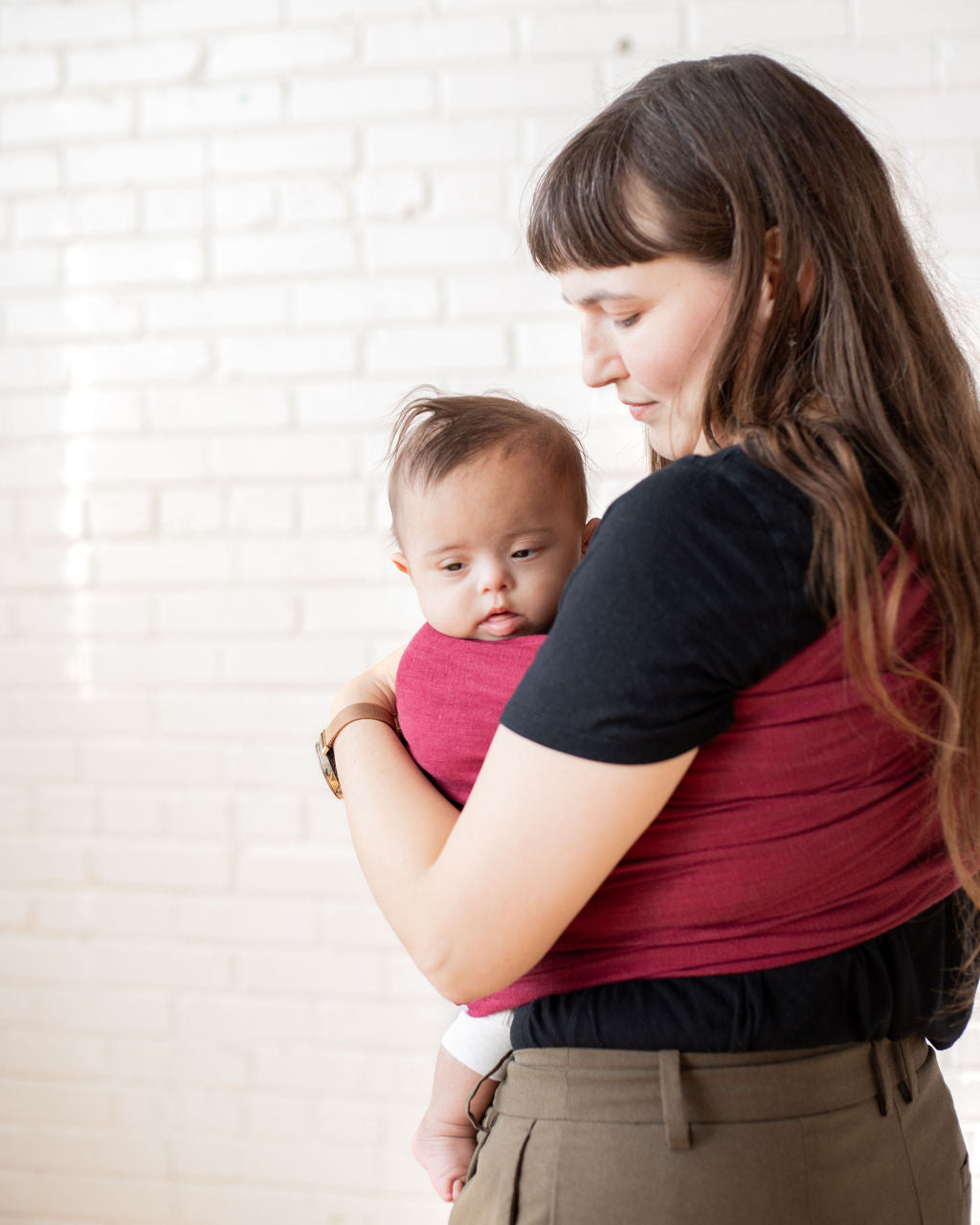 mom holding a infant in a red sling baby carrier