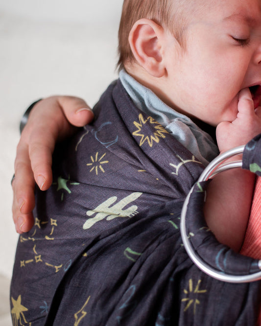newborn in a whimsical celestial printed linen ring sling baby carrier