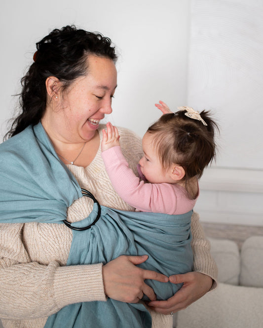 Woman babywearing a baby in a blue linen sling