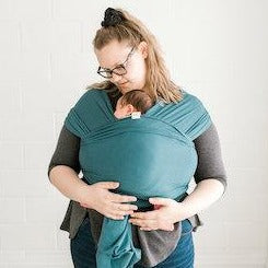 Mom with newborn baby in baby wrap carrier. Discover the top 5 babywearing benefits for parents & babies! From baby carrier wraps to ring slings, learn why it’s the best baby carrier hack.