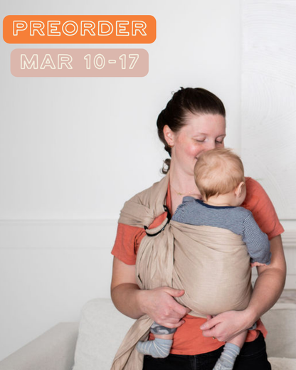 Woman holding a baby in a neutral beige ring sling 