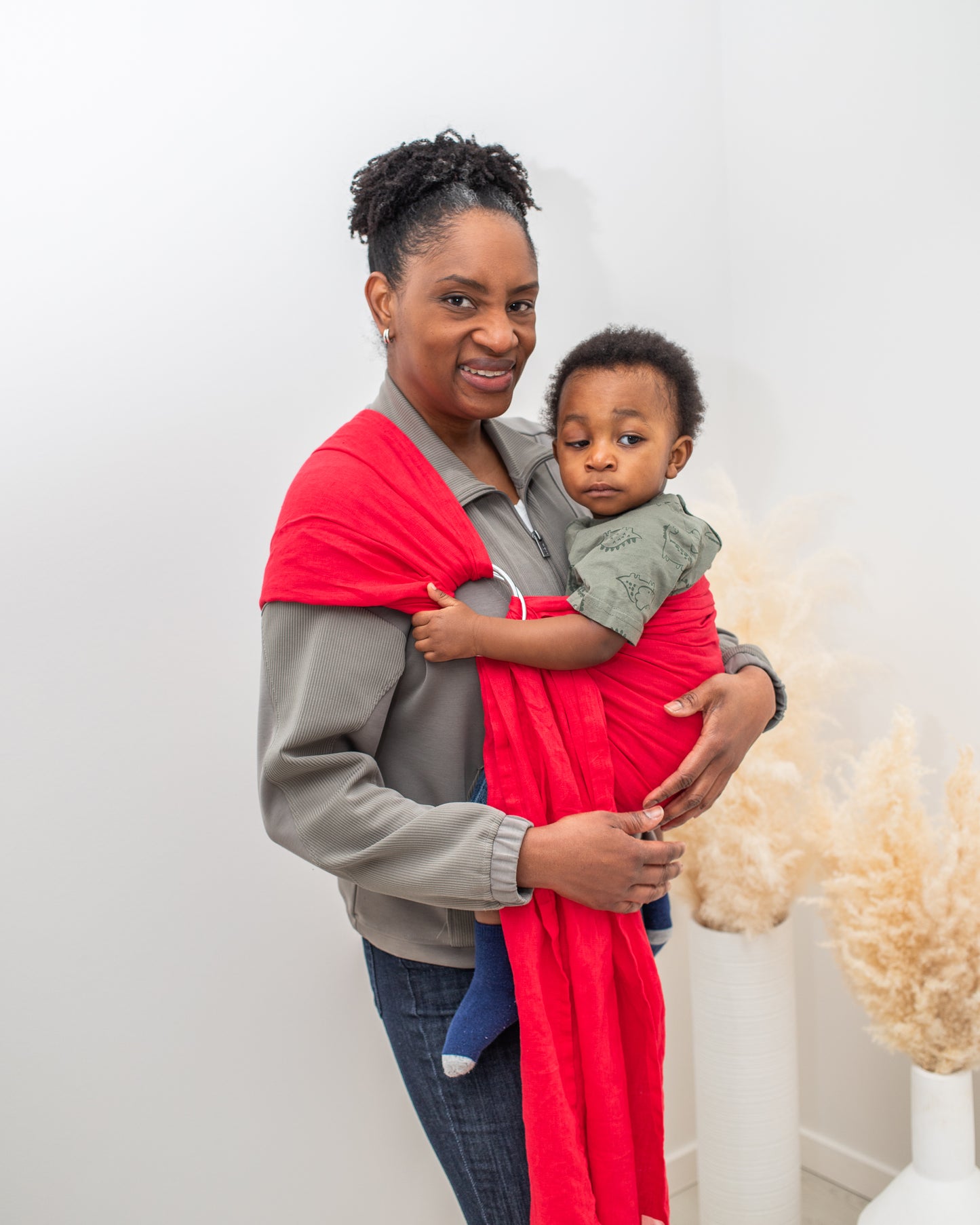 black woman wearing black toddler boy in a linen red ring sling baby carrier