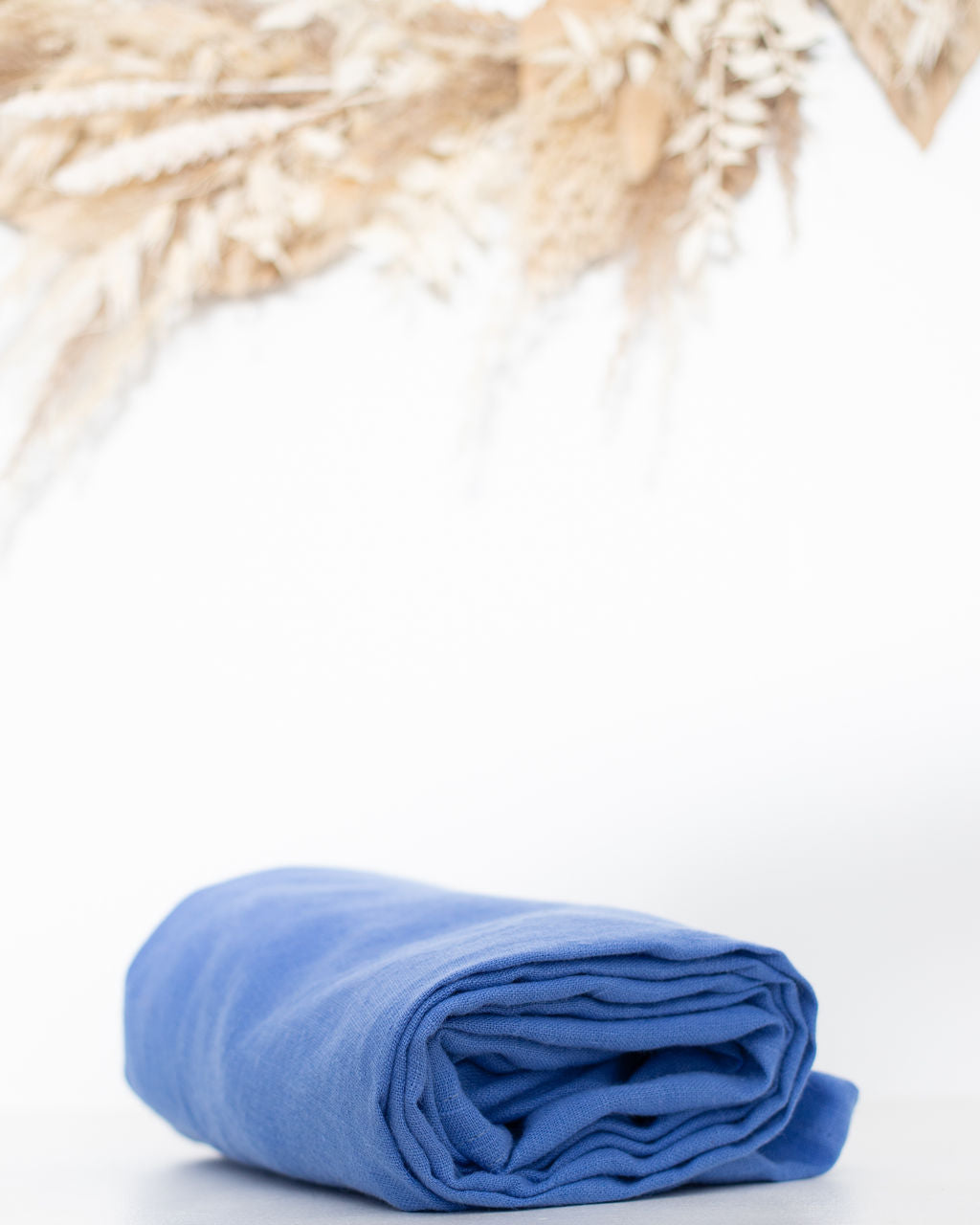 Rolled-up blue linen ring sling on a white  background