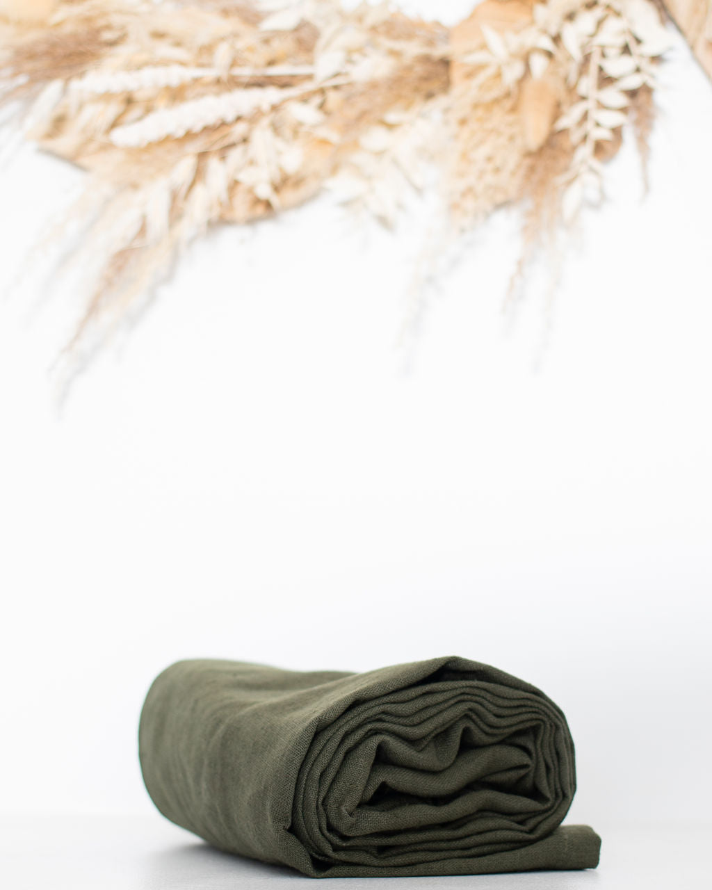Rolled-up green linen ring sling on a white background