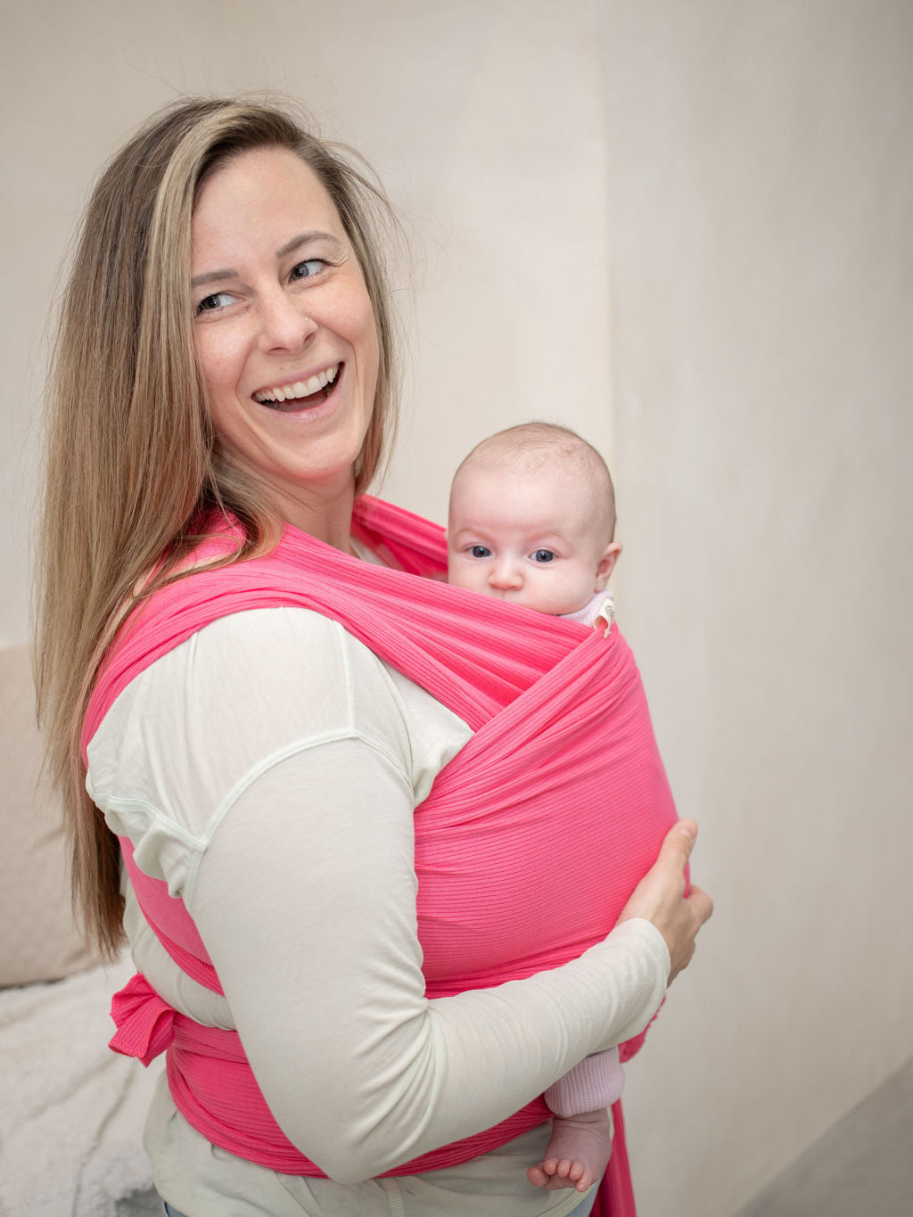 Mom wearing baby in hot pink stretchy wrap carrier. 