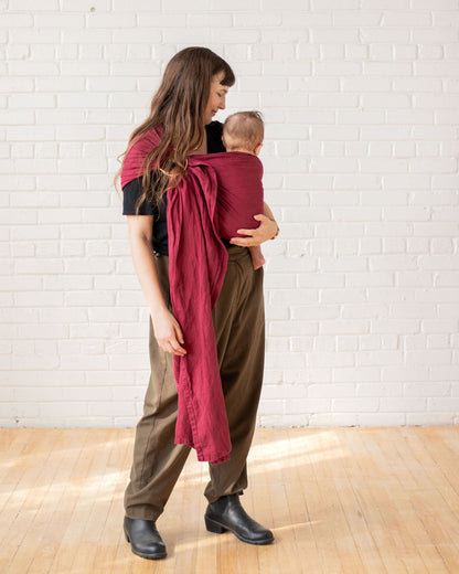 Woman wearing a baby in a cranberry red ring sling 
