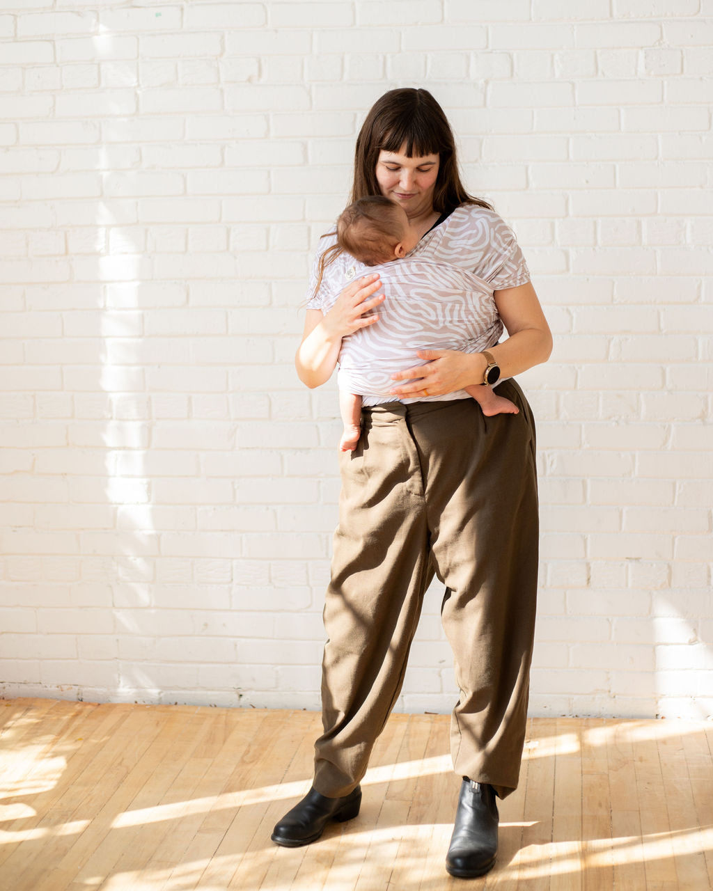 mom holding an infant in an abstract pattern stretch wrap baby carrier 