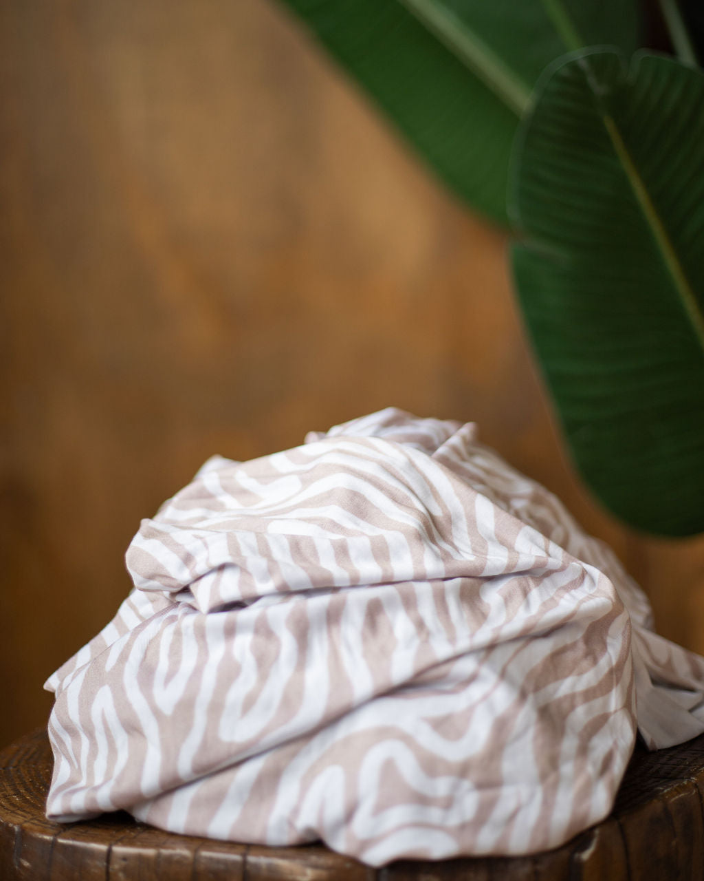 Essex subtle abtrasct patterned stretch wrap baby carrier fall product photo on a stump with a blurred green leaf in the background