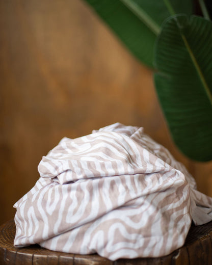 Essex subtle abtrasct patterned stretch wrap baby carrier fall product photo on a stump with a blurred green leaf in the background