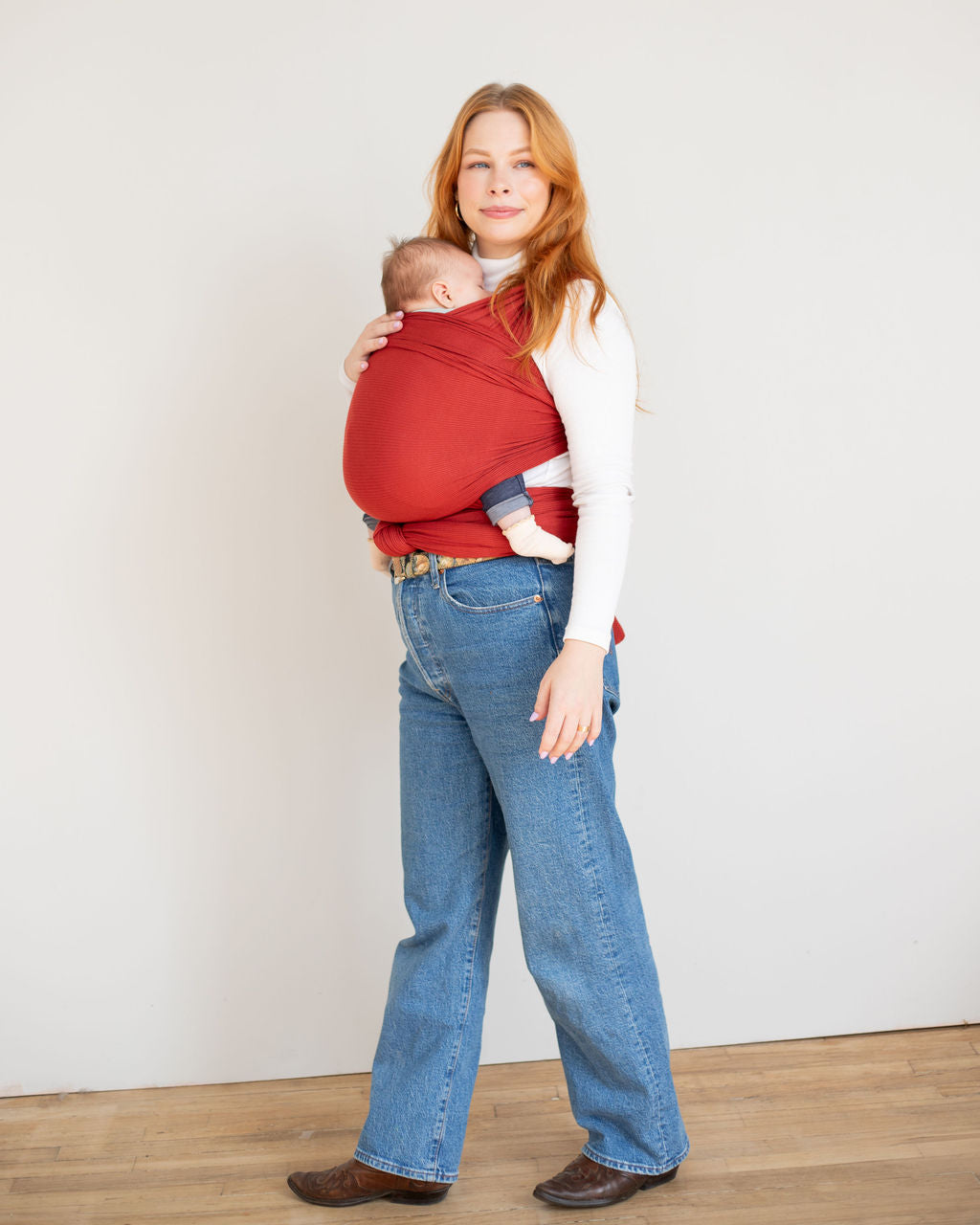 mother wearing a baby in a red stretch wrap baby carrier