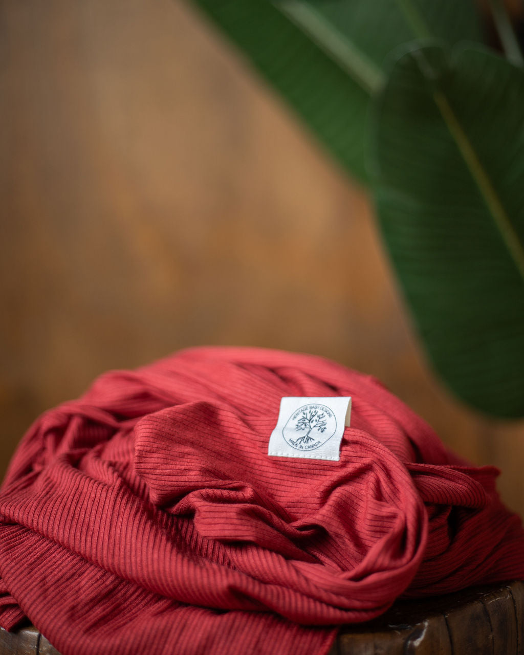 Leon (Red/Orange) Stretch Wrap Baby Carrier, Fall Product Photo on stump with leaf background