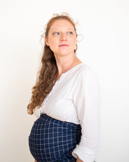 pregnant Woman wrapping belly for support with a blue plaid ring sling