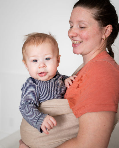 Woman wearing a baby in a beige linen ring sling 