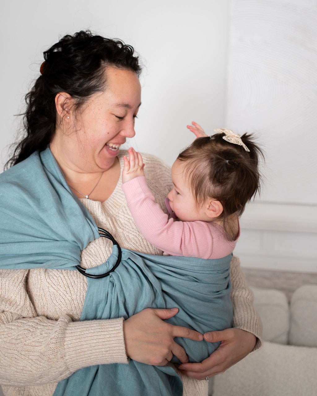 Woman babywearing a baby in a blue linen sling 