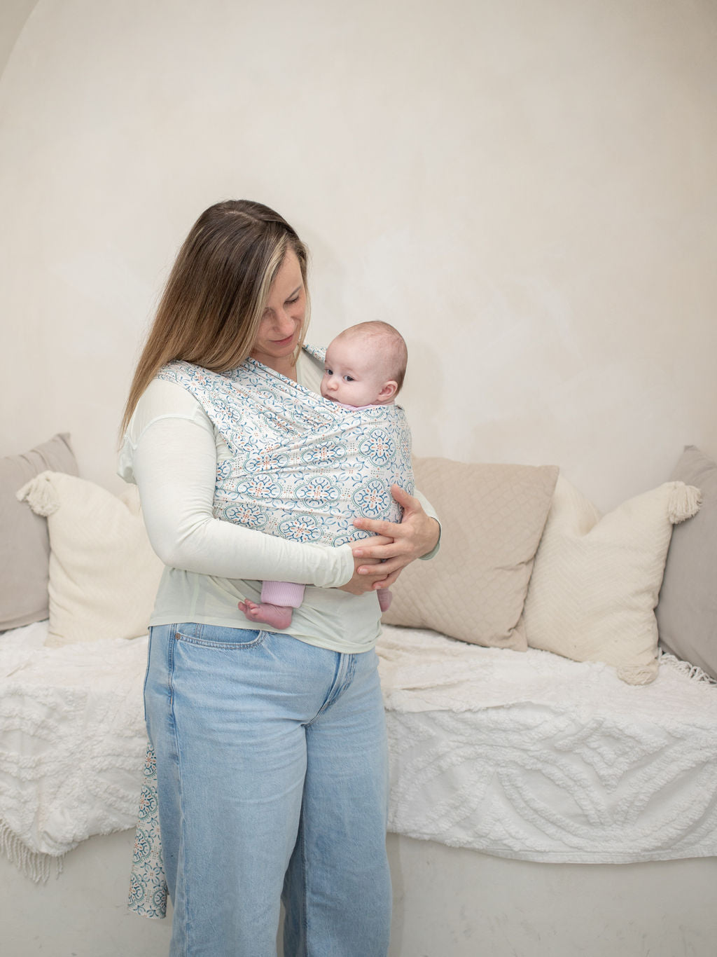 Full body shot of mom wearing infant in carrier. mom is using a strechy wrap baby carrier, in Medeira print by heritage baby designs 